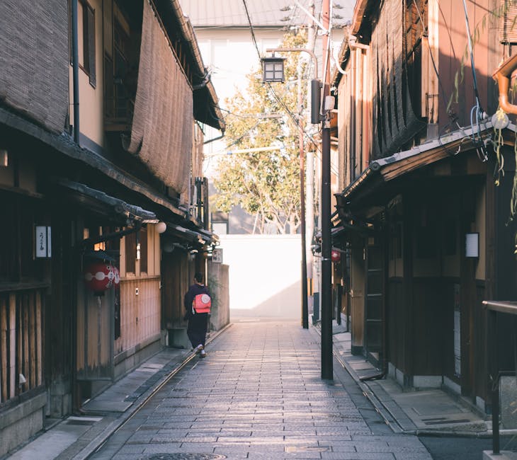A picturesque narrow alley in Gion, Kyoto, with a woman in kimono on a sunny day
